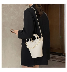 Chic white bucket bag with ring handle and metal chain strap shown on a female model