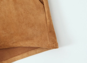 Detailed close-up of brown faux suede fabric texture and fine stitching on the jacket