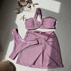 Detail of pink shimmer three-piece bikini set with a knotted skirt and beach decor