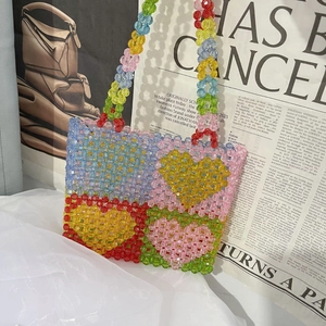 Close-up of handmade acrylic beaded tote bag featuring colorful heart pattern and woven texture