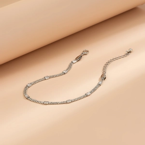 Detail of silver double-layered bead anklet with textured metal bars and lobster clasp