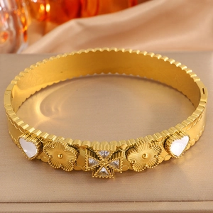 Close-up of gold titanium heart bangle with white shell inlay and zircon floral details
