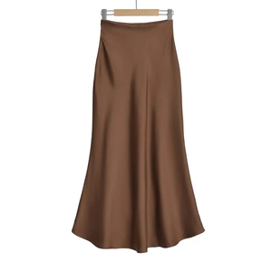 Détail d'une jupe longue en satin marron avec une texture soyeuse et un fini brillant