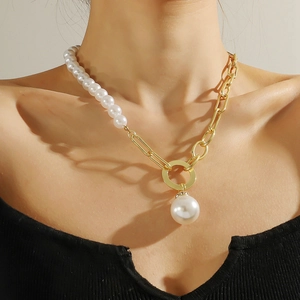 Detailed view of a gold chain necklace with baroque pearls on a model's collarbone