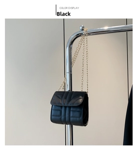 Detail of black quilted leather shoulder bag with fine golden chain strap hanging on rack