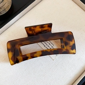 Detailed close-up of a tortoiseshell acetate hair claw clip with a hollow rectangular design