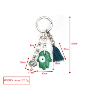 Detailed view of evil eye keychain with Fatima hand, tree of life charm, and blue tassel