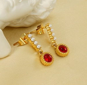Detailed close-up of vintage gold earrings with pearls and a red gemstone on silk