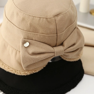 Close-up of bow knot and plush faux shearling trim on khaki and black winter bucket hats