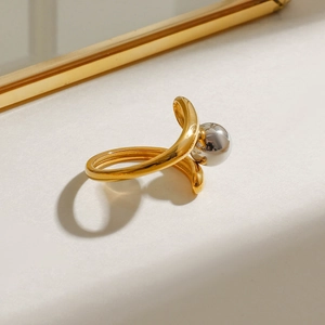Detail of two-tone stainless steel open ring with a silver bead and polished finish