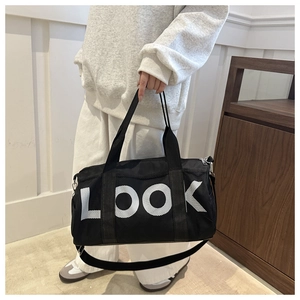 Detail of black gym bag with mesh panels and LOOK lettering held by a model