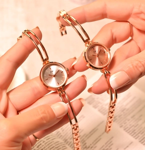 Close-up of dual rose gold chain bracelet watches with minimalist round dials for women
