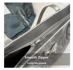 Detailed view of silver marble tote bag featuring smooth metal zipper and butterfly charm