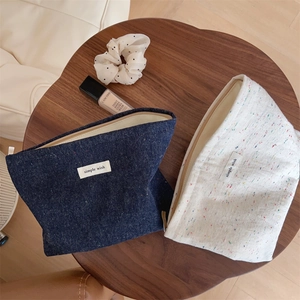 Detail of simple wish makeup bags in navy and cream with colorful speckles and metal zipper