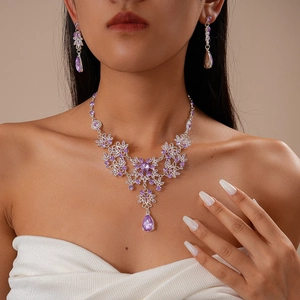 Detail of a purple gemstone flower necklace and teardrop earrings set on a model