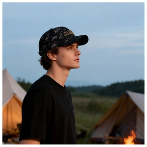 Détail d'une casquette noire avec broderie ARQ dorée et fond de camping en montagne