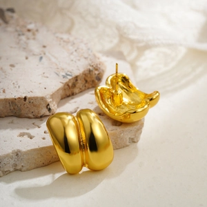 Detailed macro view of 18K gold-plated double-layer arched earrings on natural stone
