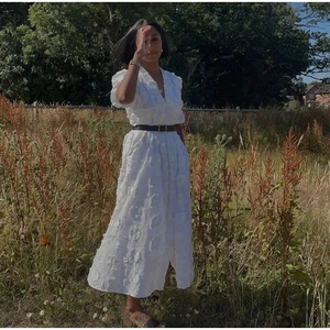 Détail de la robe midi blanche à col en V avec broderie florale sous la lumière naturelle