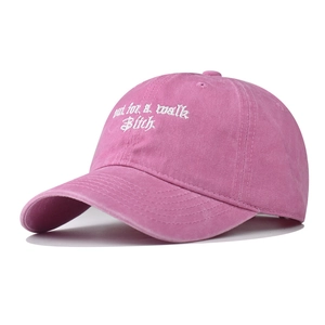 Detailed close-up of pink washed cotton baseball cap with white slogan embroidery