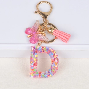 Detail of resin letter D keychain with glitter, pink tassel and butterfly charm