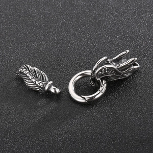 Macro detail of polished stainless steel dragon head clasp and silver feather pendant