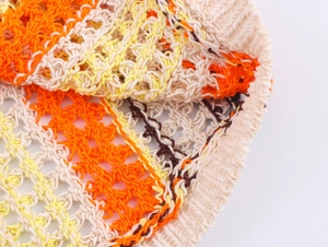 Détail de l'ensemble polo en maille crochetée bicolore avec motifs ajourés orange et beige