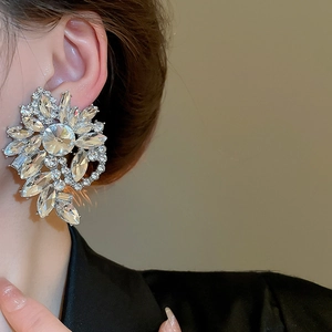 Detailed close-up of a large silver flower stud earring with sparkling crystal stones