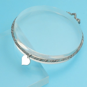 Detailed view of silver heart charm on woven Milanese cord bracelet with polished finish