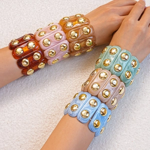 Close-up of colorful resin acrylic bracelets featuring gold studs and marbled textures