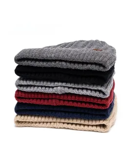 Vertical stack of six thick ribbed knit beanies in multiple colors with leather logo detail