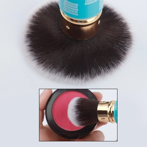 Detail of soft gradient synthetic bristles on a retractable powder brush with blue handle
