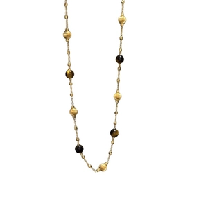 Collier vintage plaqué or 18k avec perles œil de tigre sur un fond blanc minimaliste