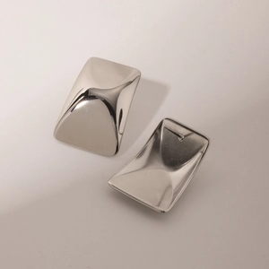 Close-up of silver stainless steel earrings with polished mirror surface and curved edges