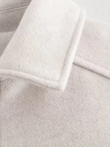 Detailed close-up of cream-colored wool jacket neckline and premium fabric texture