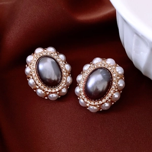 Macro detail of vintage oval earrings with grey gems and pearls on silk background