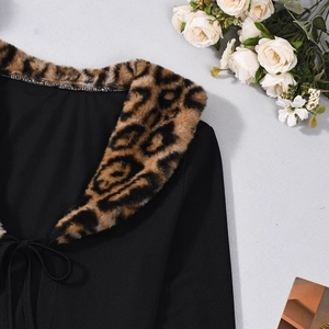 Dettaglio top in maglia nera a coste con colletto in ecopelliccia leopardata e laccetti