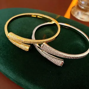 Gold and silver open bangles with green gemstones and pave-set zircons on green velvet