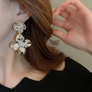 Close-up of elegant silver flower drop earrings worn by a model for a stylish metal look