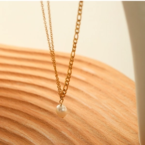 Close-up of double layer 18K gold titanium steel necklace with a freshwater pearl pendant