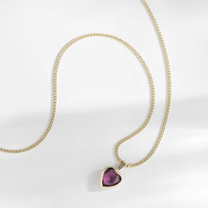 Detailed close-up of a delicate golden chain with a purple heart-shaped topaz pendant