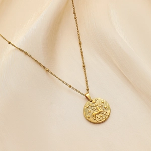 Detailed close-up of gold Sagittarius zodiac relief coin necklace on soft beige silk fabric