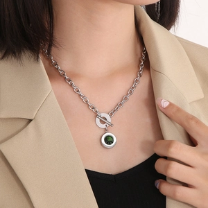 Detailed close-up of chunky silver chain necklace with OT toggle clasp and green stone pendant