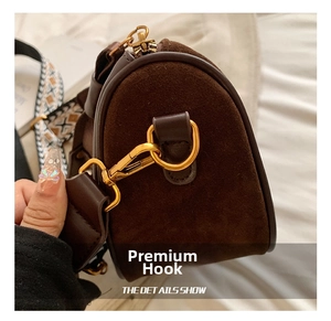 Detail of brown suede bag featuring gold D-ring hardware and jacquard woven strap
