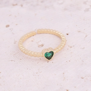 Detailed macro view of a gold open ring featuring a green heart-shaped gemstone and beaded texture