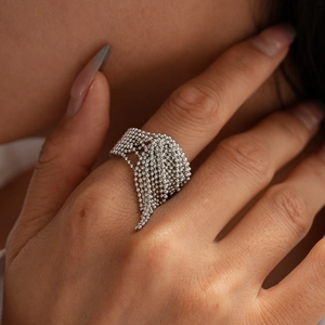 Detail eines silbernen Perlen-Tassel-Rings mit mehrlagigen Metallkugeln am Finger