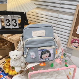 Vue détaillée du petit sac en toile bleu clair avec fente PVC et pendentif d'ours doux