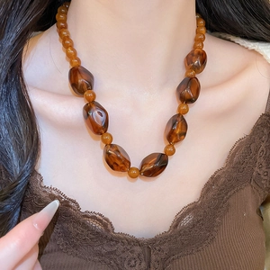 Detail of irregular amber acrylic beads on a vintage brown necklace worn by a model