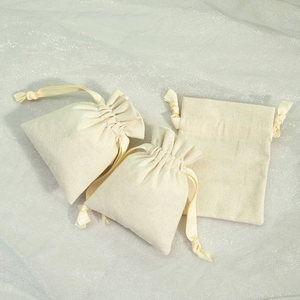 Three beige cotton linen drawstring pouches on textured background for jewelry storage