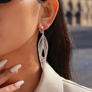 Close-up of geometric hollow silver earrings with leaf lattice and inlaid crystals