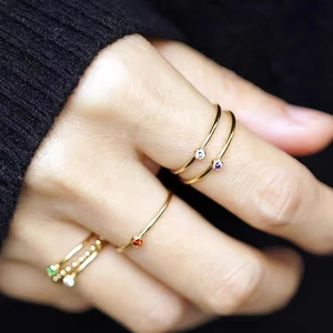 Detailed view of stacked 18K gold plated stainless steel birthstone rings on model hand